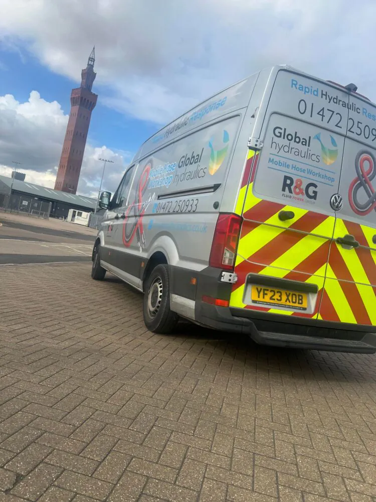 global hydraulics van on the pavement near a clock tower